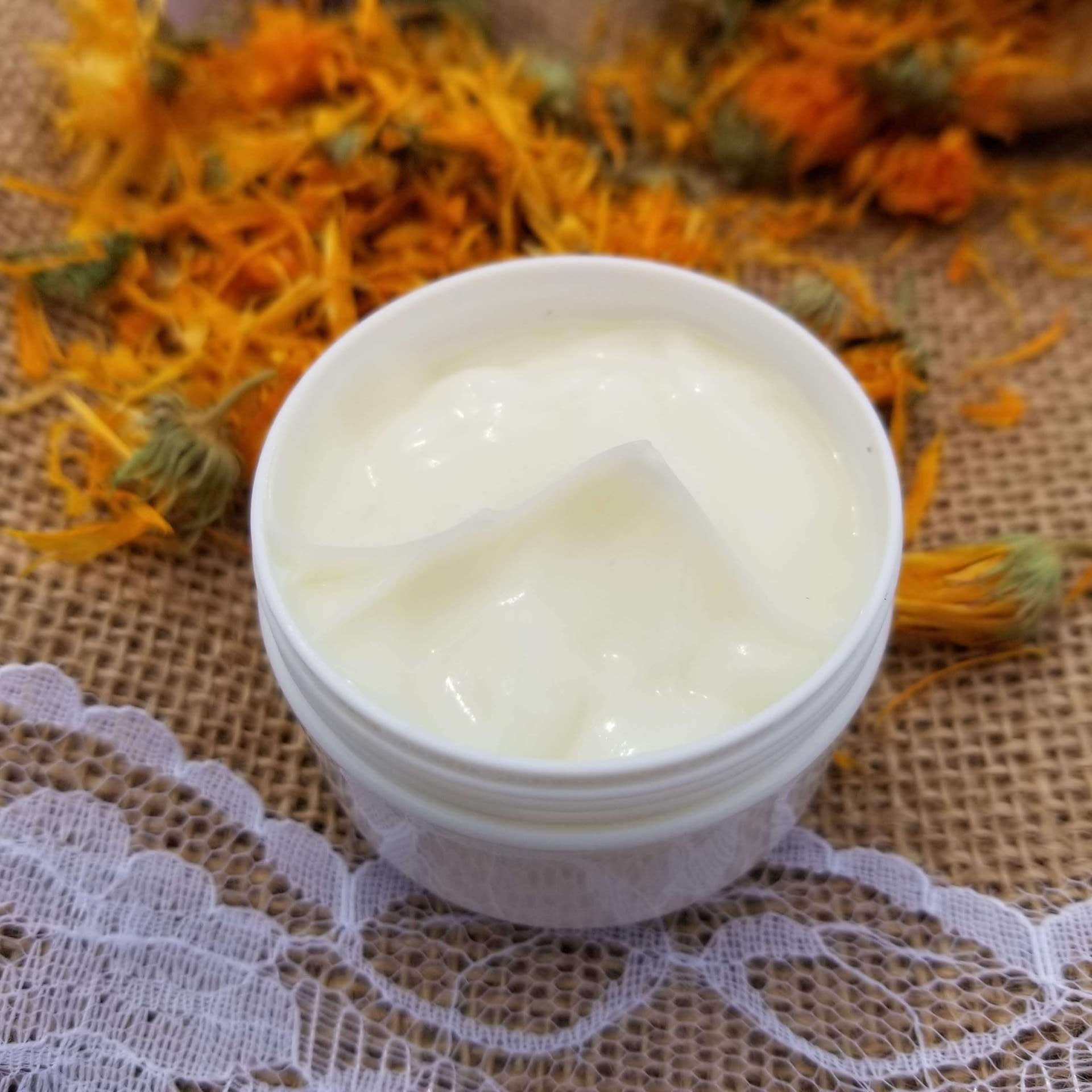 A white jar of yellowish lotion on the background with dry calendula.