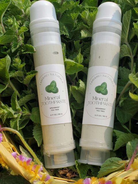 Green toothpaste in clear tubes in a basket with fresh mint