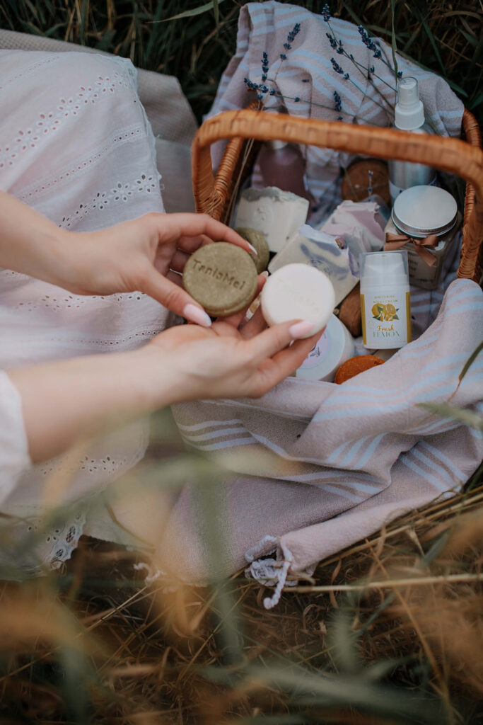 Tania's hands picking soap from a basket of her products in a field.